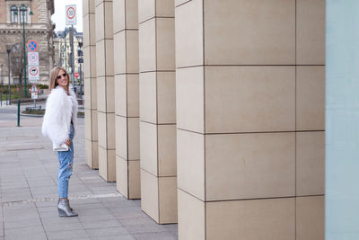 Full length portrait of woman standing by building