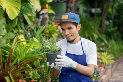 Young man smiling while standing against plants