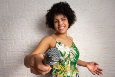 Portrait of a smiling young woman standing against wall