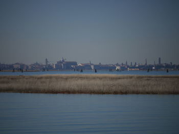 Buildings by sea against clear sky