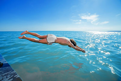 Man surfing in sea against blue sky