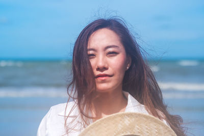 Portrait of young woman wearing hat against sea