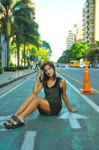 Portrait of young woman sitting on street in city