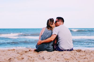 Rear view of couple on beach against sky