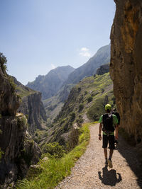 Rear view of man walking on mountain against sky