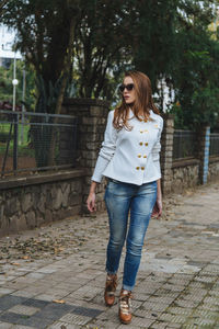 Portrait of smiling young woman standing on footpath