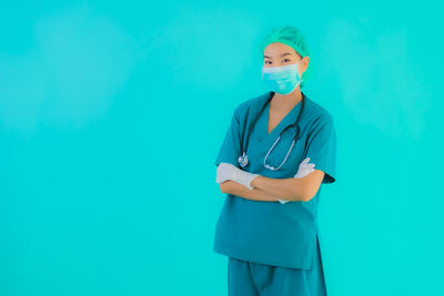 Portrait of young woman standing against blue background