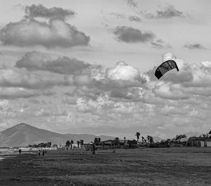 People flying kite on field against sky