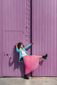 Woman with umbrella standing against pink wall