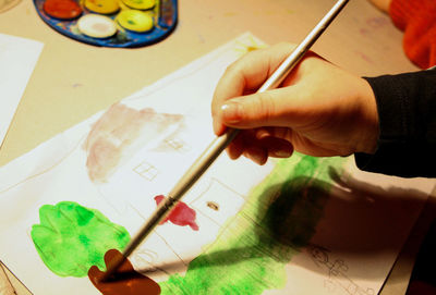 Close-up of hand holding paper with knife on table