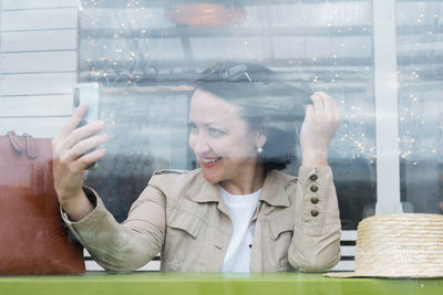 Portrait of a smiling young woman looking through window