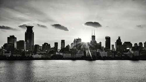 Modern buildings by river against sky in city