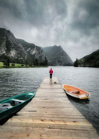 Rear view of man standing on lake against sky