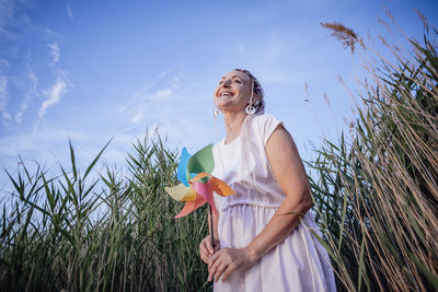 Girl with multicolored pigtails , face sideways, laughing, holding a windmill , wind energy