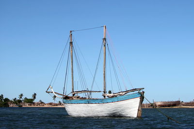 Sailboat sailing on sea against clear blue sky