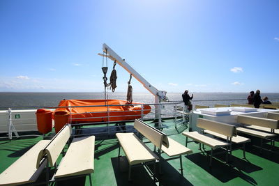 People on boat moored in sea against sky