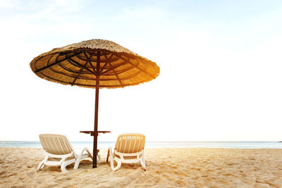 Parasols and chairs on beach against sky