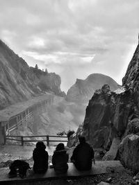 Rear view of people looking at mountains against sky