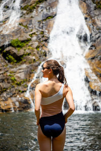 Rear view of woman standing by waterfall