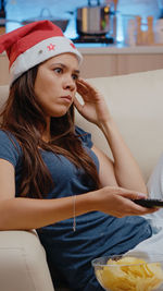 Young woman looking away while sitting on bed at home