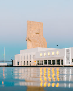 Modern building by river against clear sky