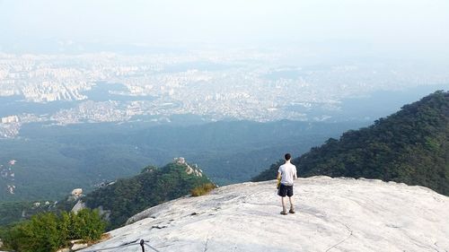Rear view of man on cliff looking at seoul, china