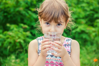 Portrait of young woman drinking water in park