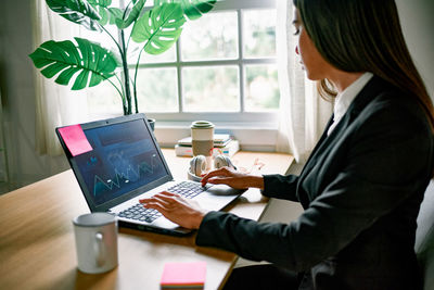 Side view of businesswoman using laptop at office