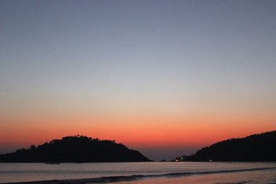 Scenic view of beach and mountains against clear sky