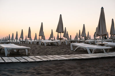 Umbrellas on the beach against clear sky during sunrise