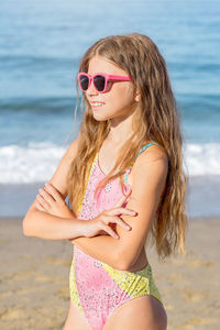 Fashion cute young girl posing on the beach in a summer swimsuit. 