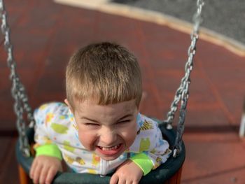 Portrait of smiling boy on swing at playground