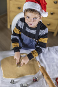 High angle view portrait of smiling boy making cookies at home