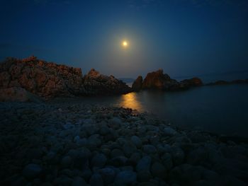 Rocks in sea against clear sky at sunset