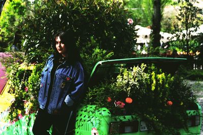 Woman standing by flowering plants against trees