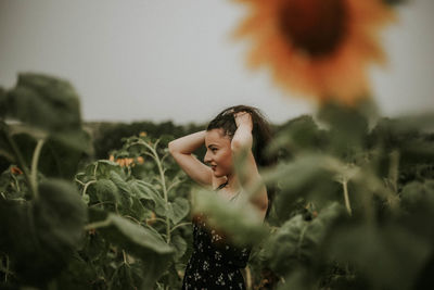 Young woman standing amidst sunflowers on field