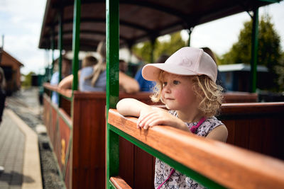 Girl looking away while standing by railing