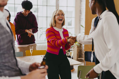 Happy businesswoman shaking hand with female colleague during event at convention center