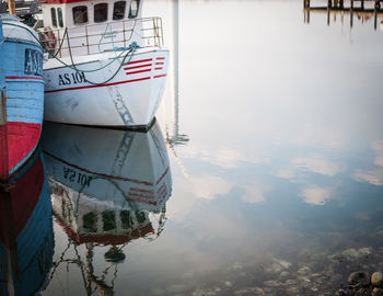 Boats moored at harbor against sky