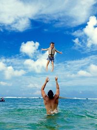 Rear view of father and son playing in sea