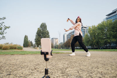 Woman filming dance on mobile phone at park