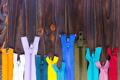 Multicolored zippers are laid out on a wooden table