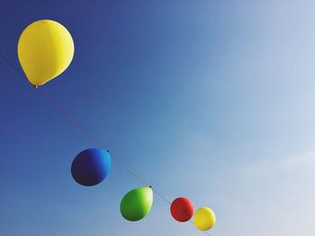 Low angle view of balloons against blue sky