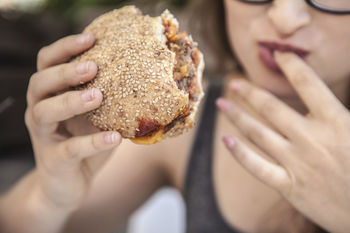 Midsection of teenage girl holding hamburger