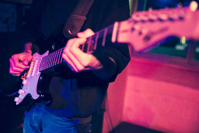 Midsection of man playing guitar