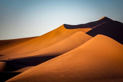 Scenic view of sand dunes at desert against clear sky