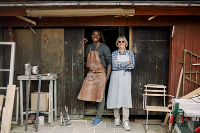 Full length portrait of smiling multi-ethnic coworkers standing at store entrance