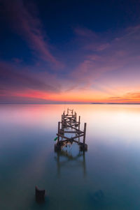 High angle view of pier ruins in calm sea at sunset