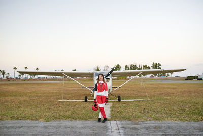 Young female skydiver in an airfield with a plane behind her