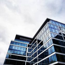 Low angle view of modern building against cloudy sky